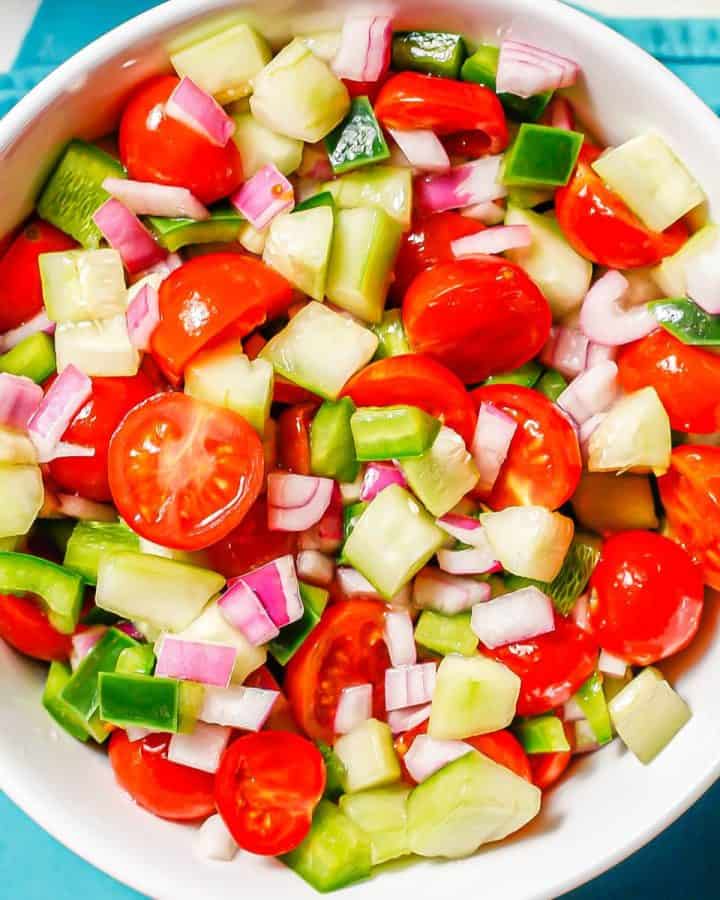Close up of a mixture of marinated fresh veggies in a large white serving bowl.