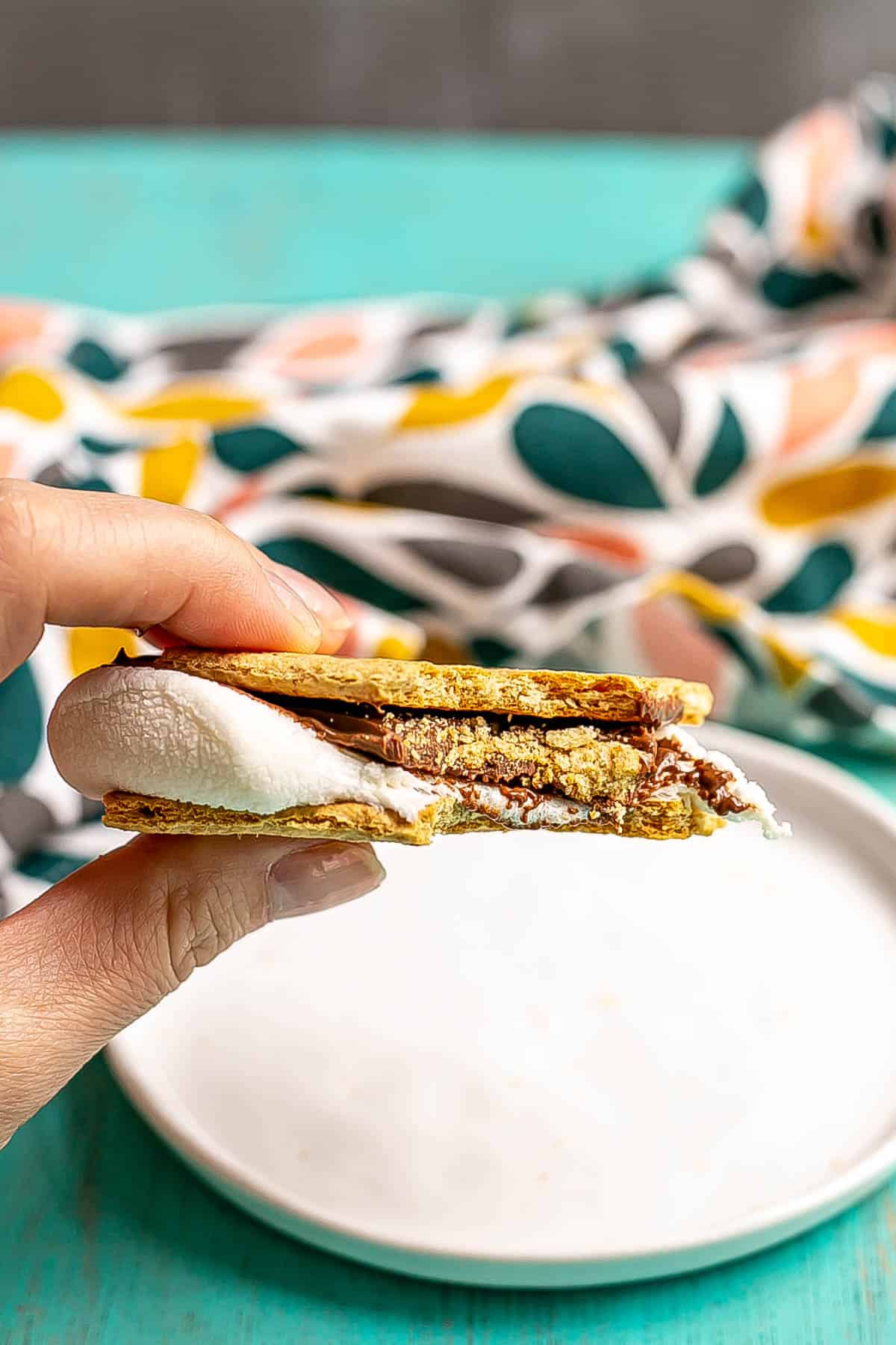 A hand holding s'mores with a bite taken out.