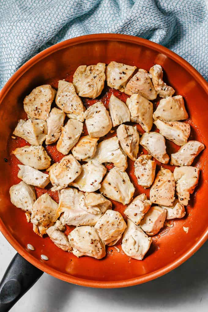 Cubed chicken pieces seared in a copper skillet.