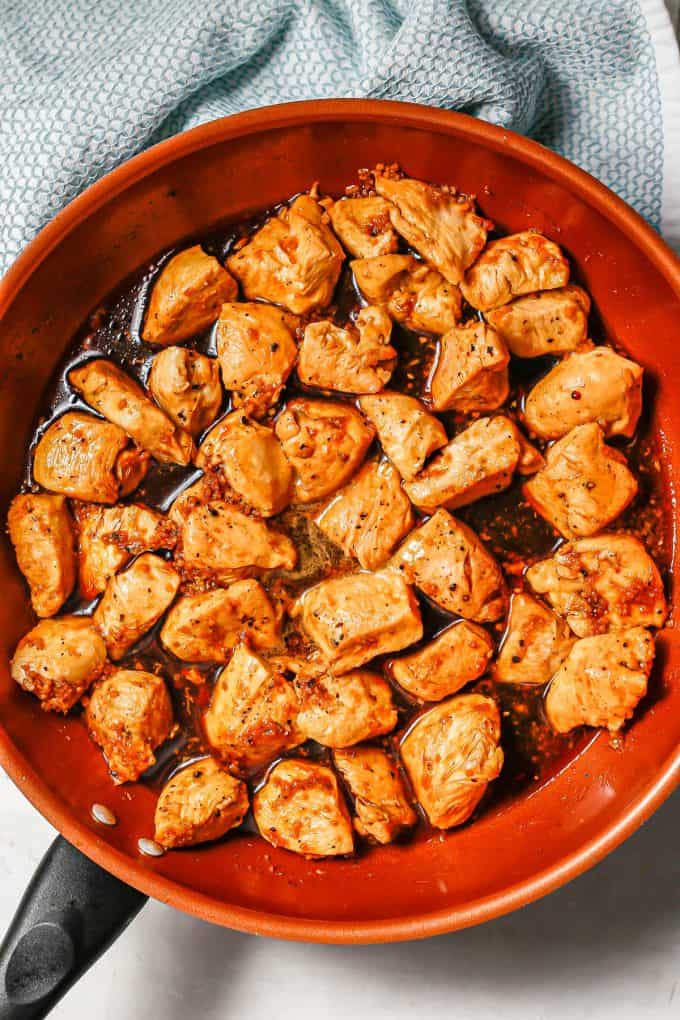 Chicken pieces in a bourbon and soy sauce mixture in a large copper skillet.