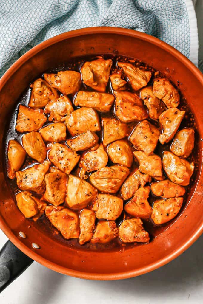 Chicken in a dark sauce in a large copper skillet.