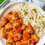 Bourbon chicken served with rice and sliced green onions in a low white bowl with a text overlay on the photo.