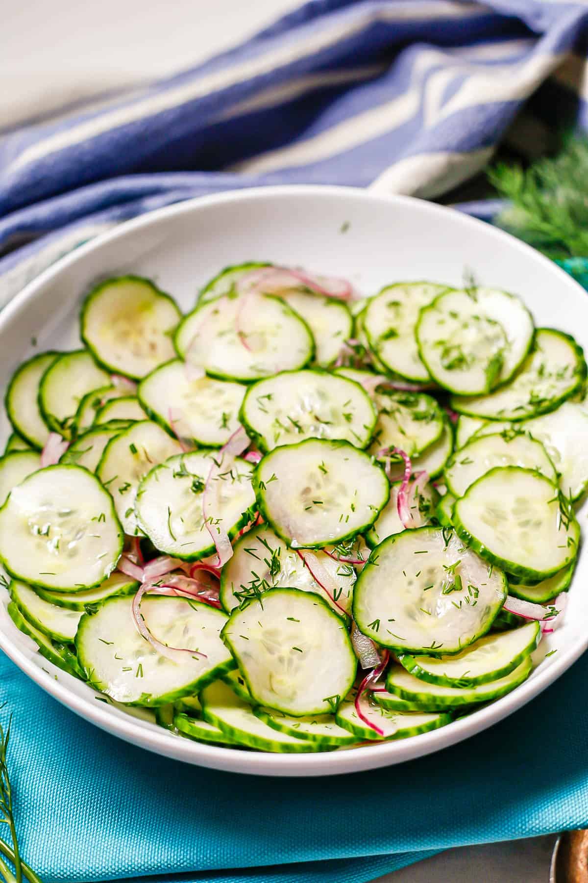 A cucumber salad in a red wine vinaigrette served in a white bowl.