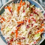No mayo coleslaw in a blue and white bowl with colorful napkins nearby and a text overlay on the photo.