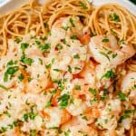 Close up of garlic butter shrimp over pasta in a low white bowl with a text overlay on the photo.
