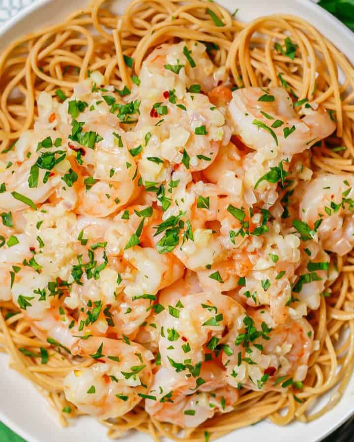 Shrimp and sauce served over noodles in a white bowl.