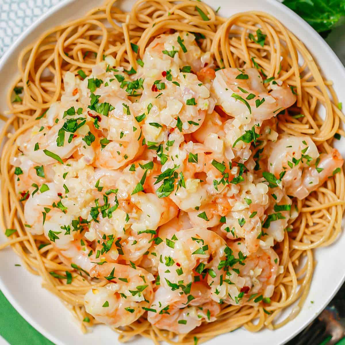 Shrimp and sauce served over noodles in a white bowl.