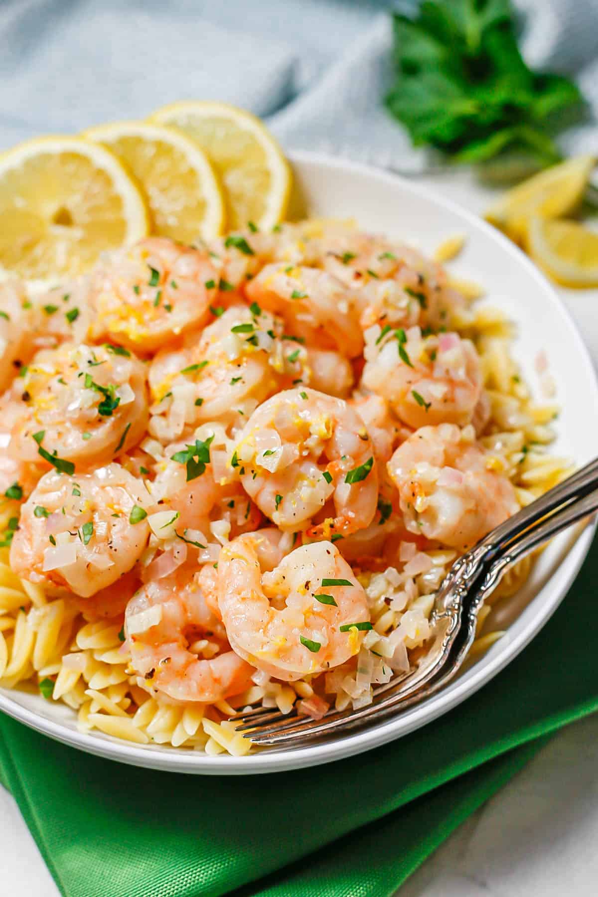 Forks resting in a bowl of lemon garlic shrimp and orzo pasta.