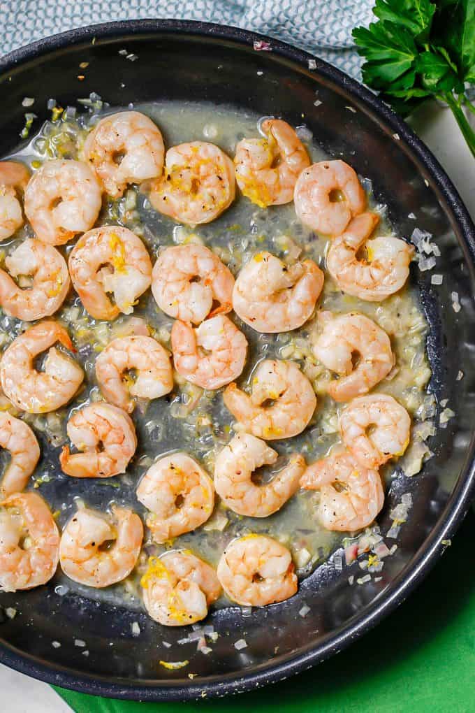 Close up of shrimp in a white wine sauce in a large skillet.