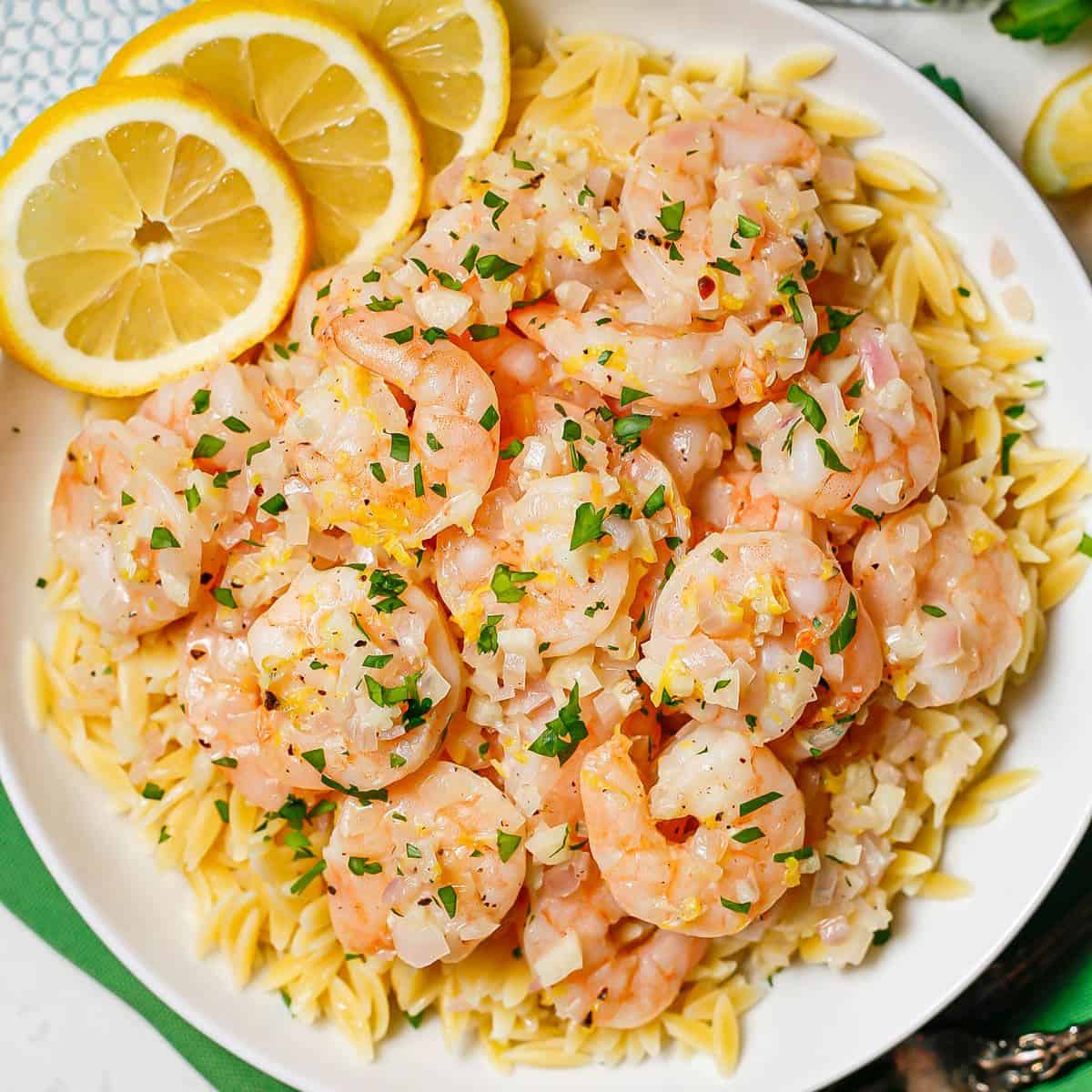 A low white bowl with lemony shrimp served over orzo pasta.