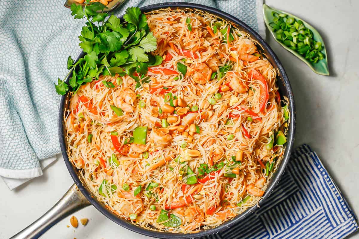 Shrimp pad Thai served with sliced green onions on top and some extra in a dish to the side.
