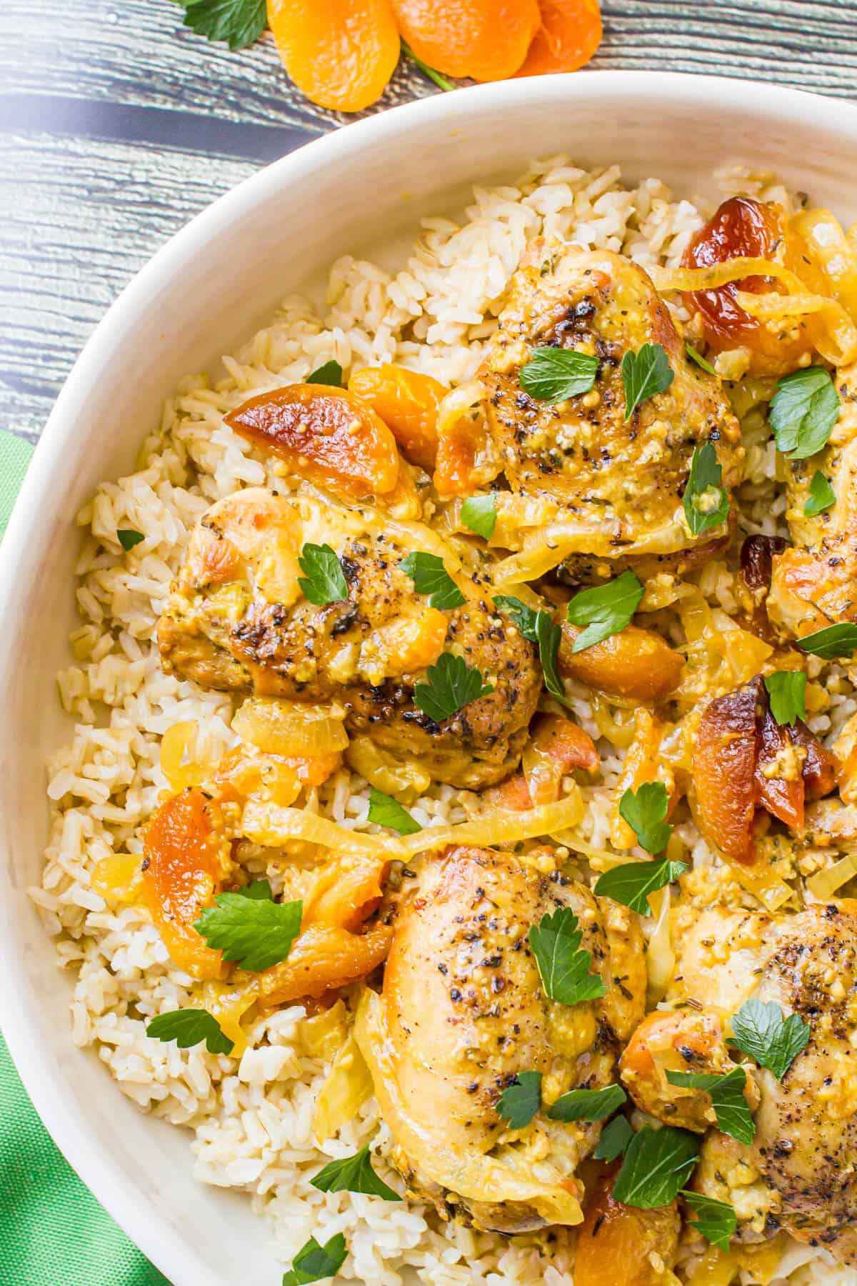 Apricot chicken served over rice in a large round white serving platter.