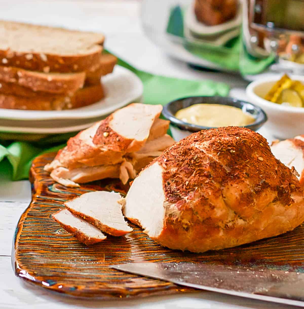 A boneless turkey breast on a cutting board with some slices carved out.