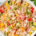 A bright, fresh summer farro salad with fresh veggies and basil in a white serving bowl with a text overlay on the photo.
