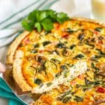 A piece of veggie lovers quiche being lifted out from the pie plate and a text overlay on the photo.