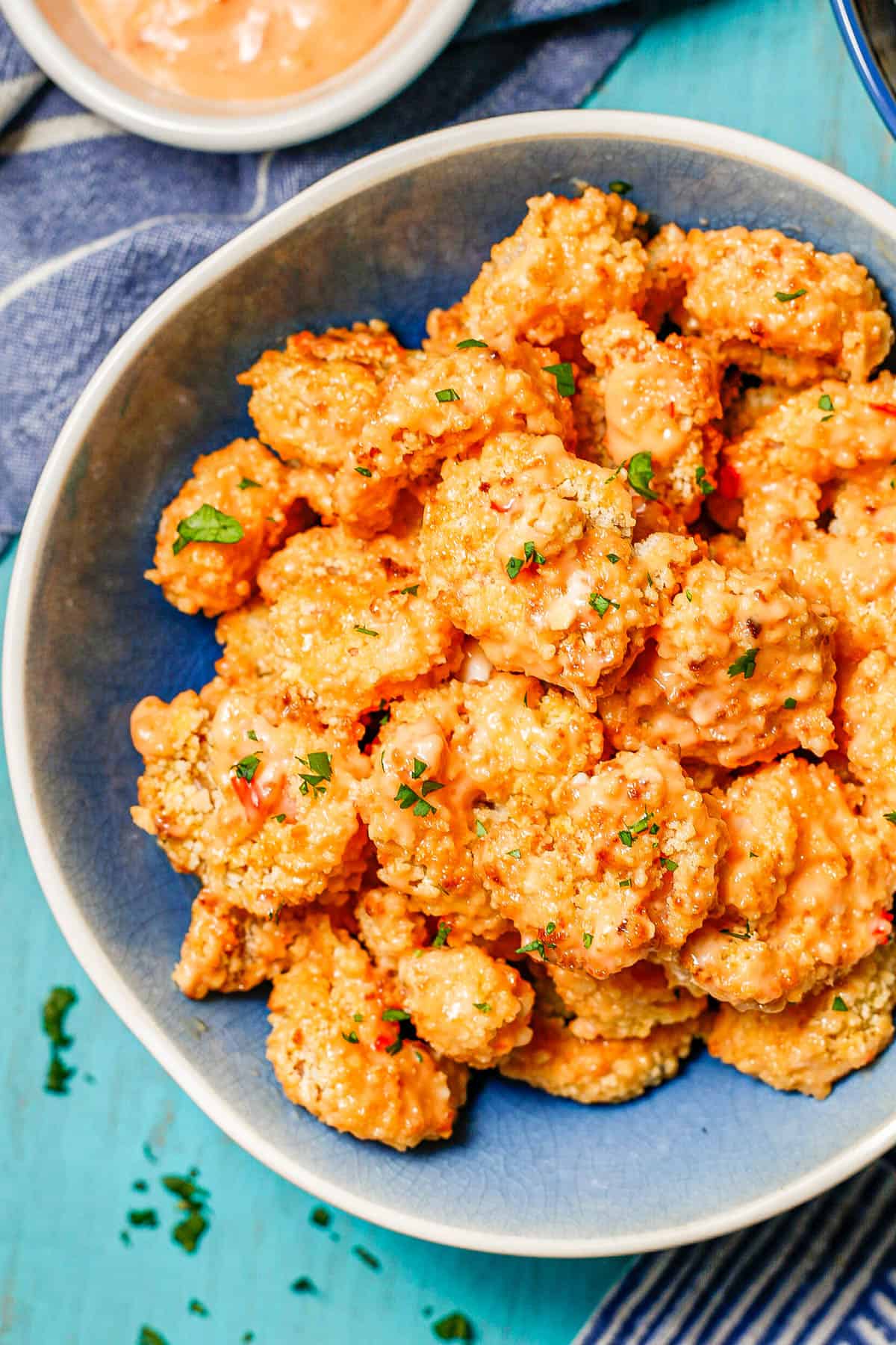 Close up of bang bang shrimp served in a blue and white bowl.