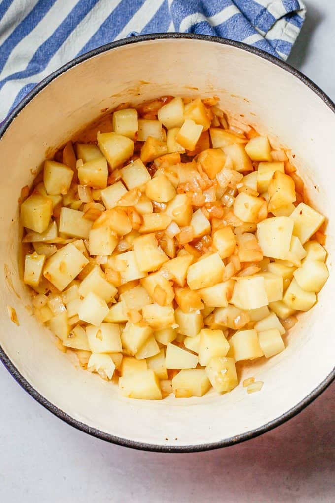 Potatoes and onions being cooked in a large deep pot.