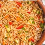 Close up of spaghetti salad with tomatoes, carrots, green peppers and cucumber with Italian dressing and salad seasoning and a text overlay on the photo.