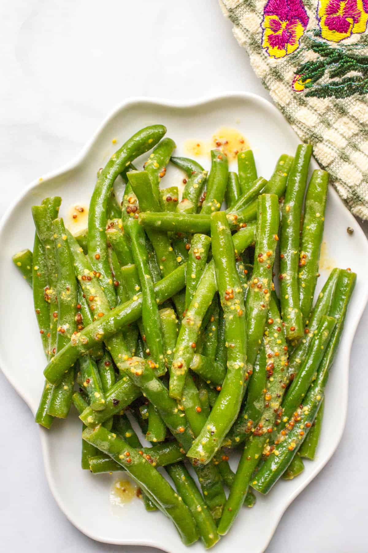 Green beans with mustard butter sauce served on a white platter.