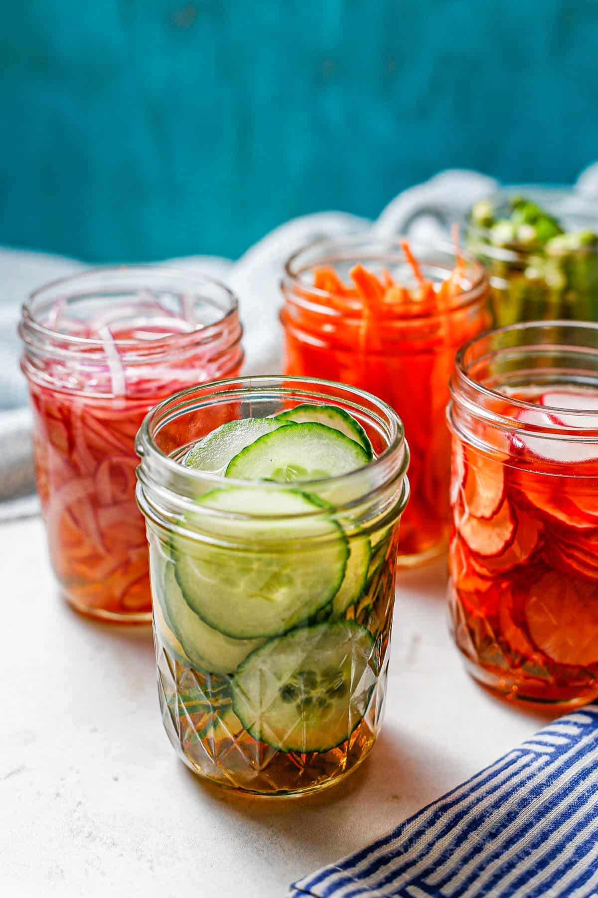 Small glass mason jars with different pickled vegetables.