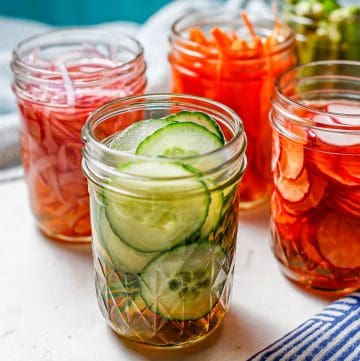 Close up of small glass mason jars with different pickled vegetables.
