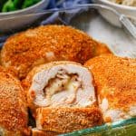 Close up of a glass casserole dish with baked chicken cordon bleu with one sliced to show the inside stuffing with a text overlay on the photo.