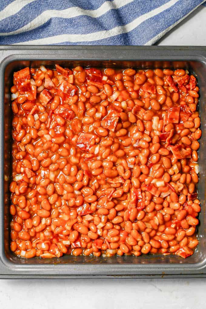 A square pan with baked beans before being cooked.