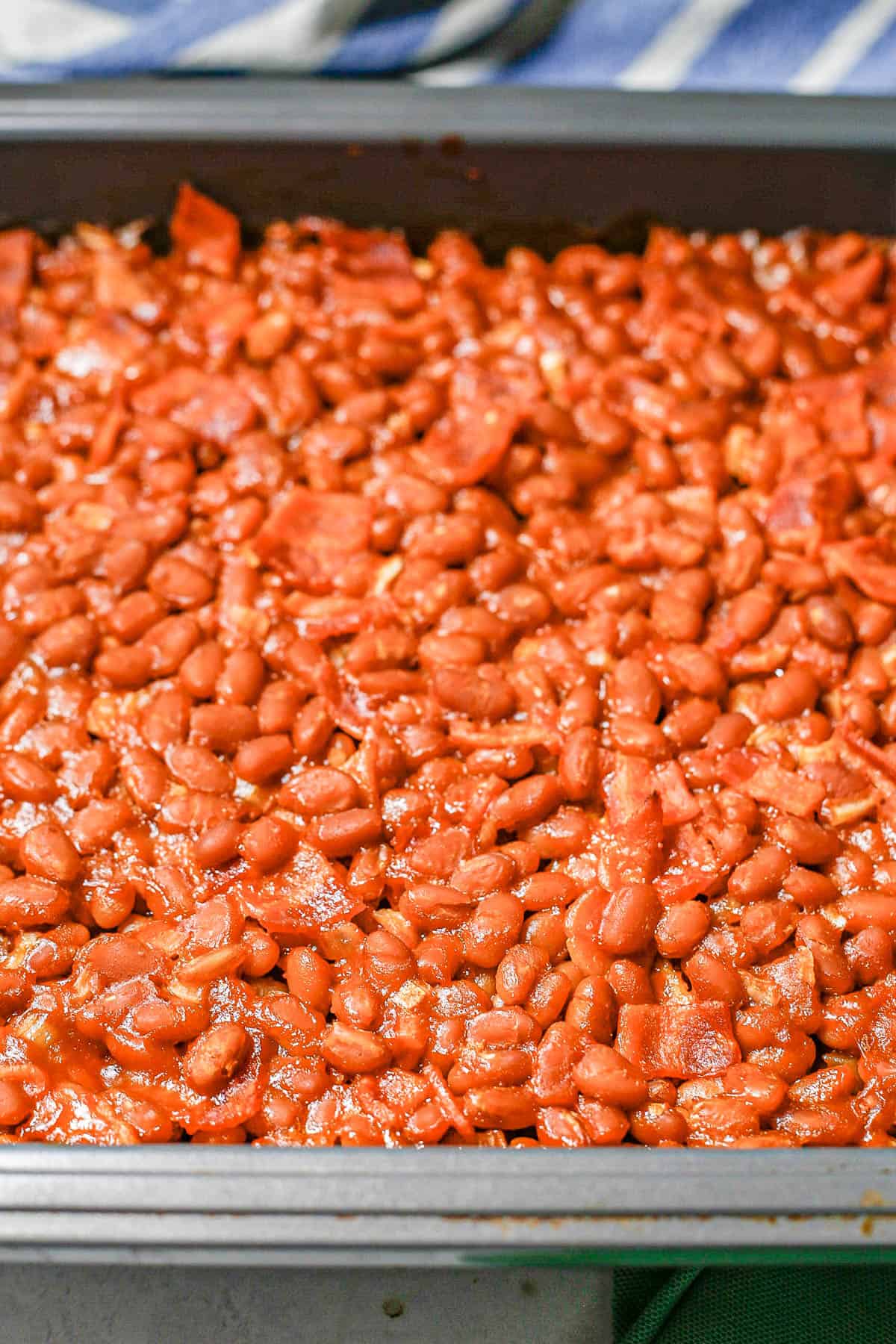 Saucy baked beans in a square nonstick pan after being cooked.