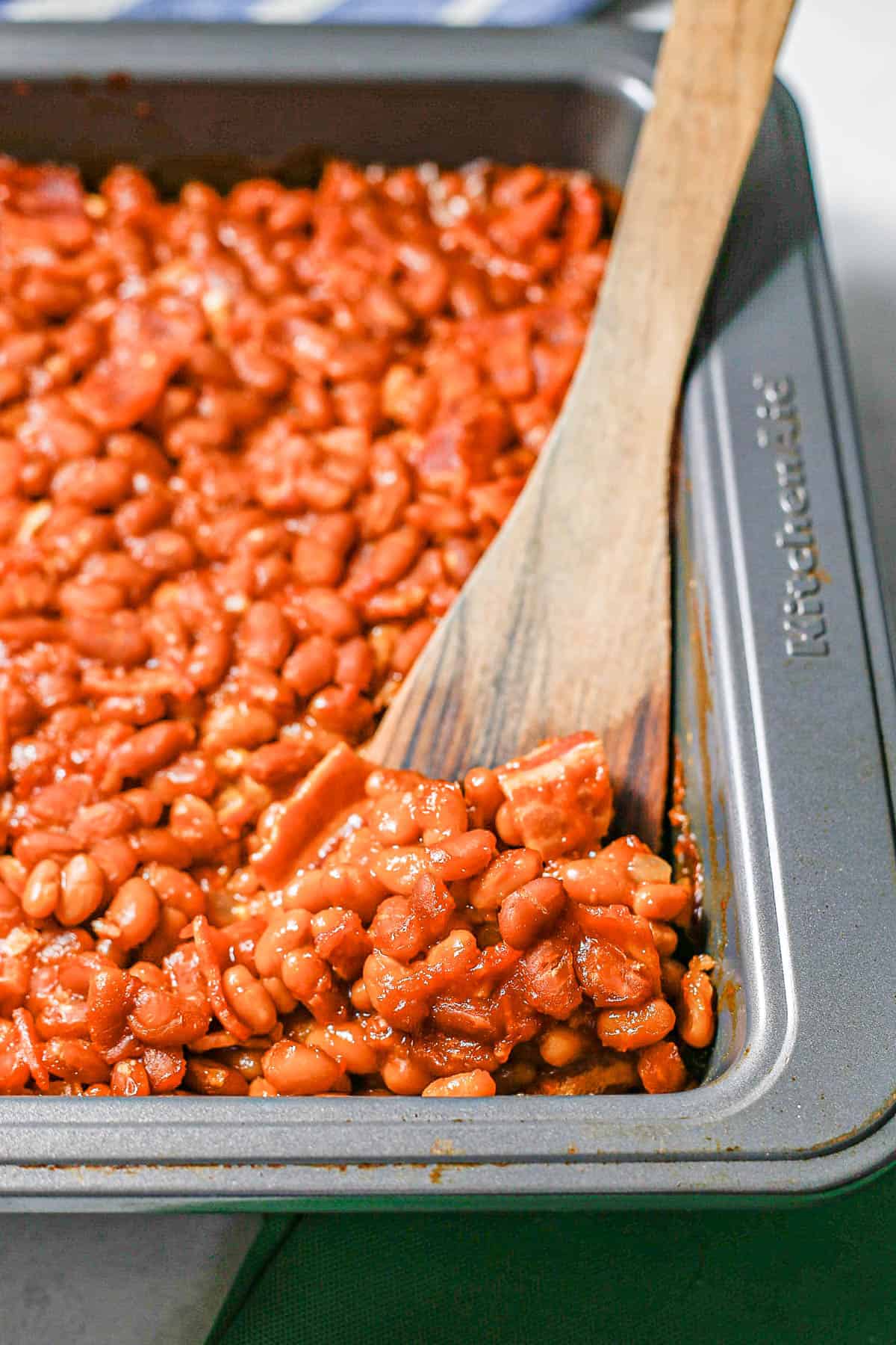 A wooden spatula resting in a pan of baked beans.