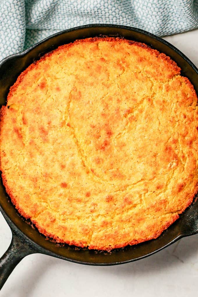 Baked golden brown cornbread in a cast iron skillet.