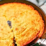 A pie server lifting up a slice of cornbread from a cast iron skillet with a text overlay on the photo.