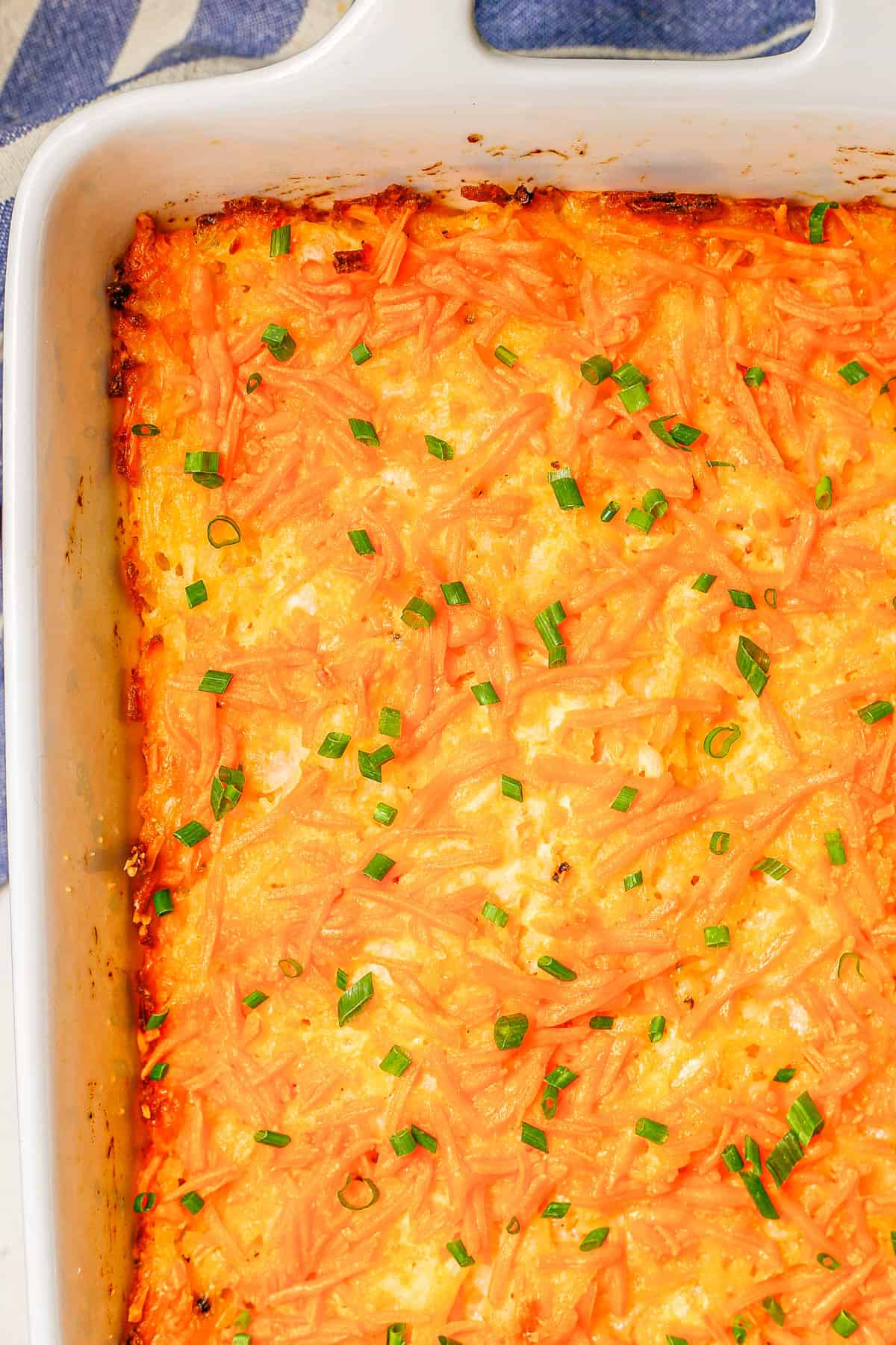 Cheesy hash brown casserole in a white rectangular casserole dish.