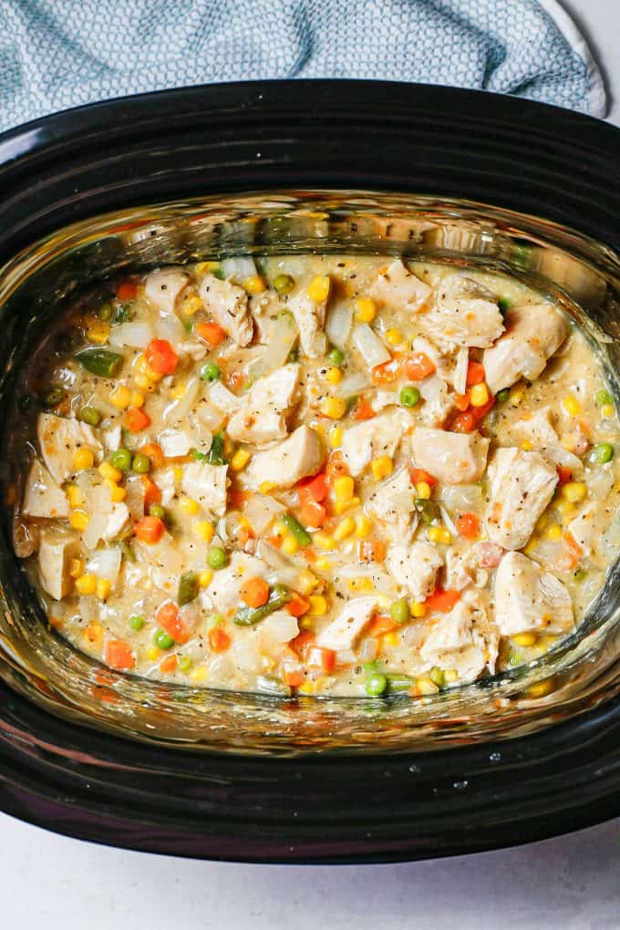 Chunks of chicken with a mixture of vegetables and a creamy gravy in a slow cooker.