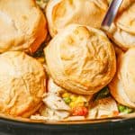A silver ladle scooping up chicken pot pie and a biscuit from a slow cooker with a text overlay on the photo.