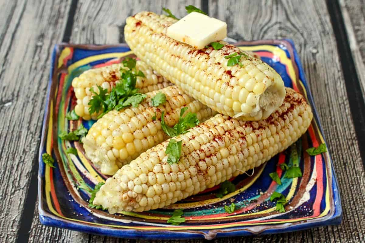 Cooked corn on the cob with parsley, chili powder and butter.