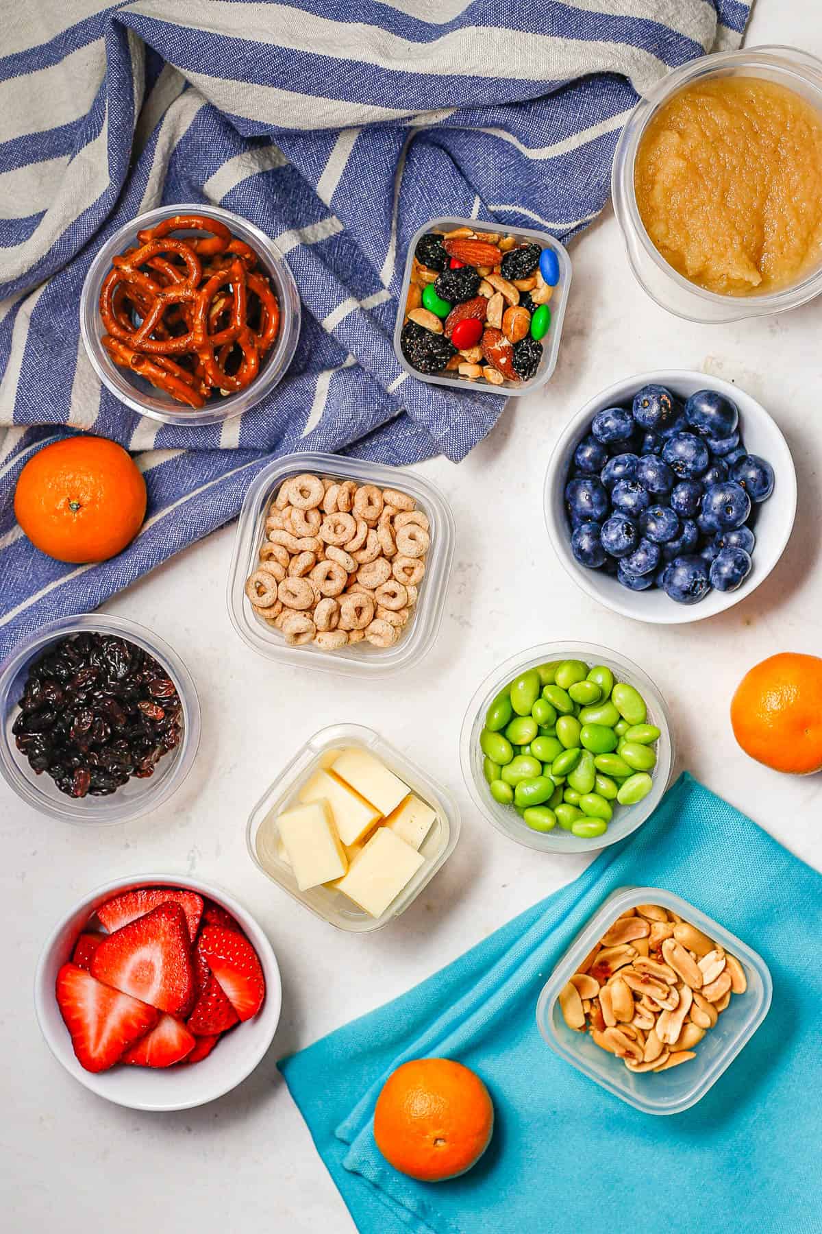 A collection of tiny containers with different colorful healthy kids snacks on a counter.