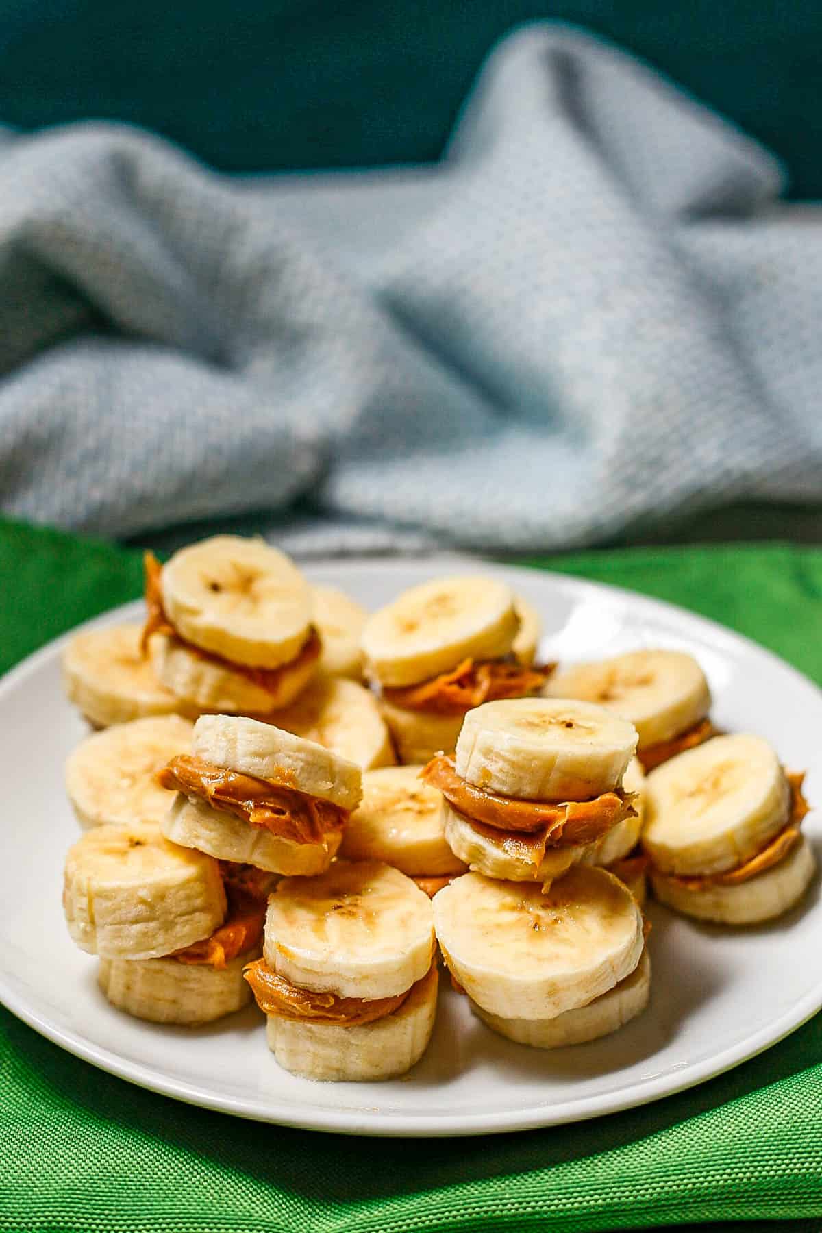 A plate full of sliced bananas stacks with peanut butter sandwiched in the middle.