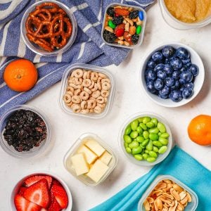 Close up of a collection of tiny containers with different colorful healthy kids snacks on a counter.