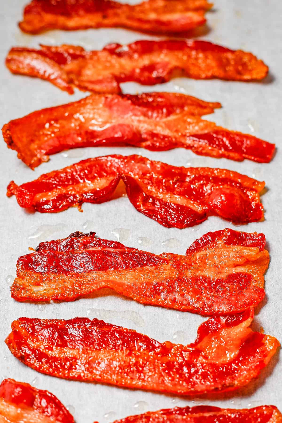 Crisp cooked bacon on a piece of parchment paper.