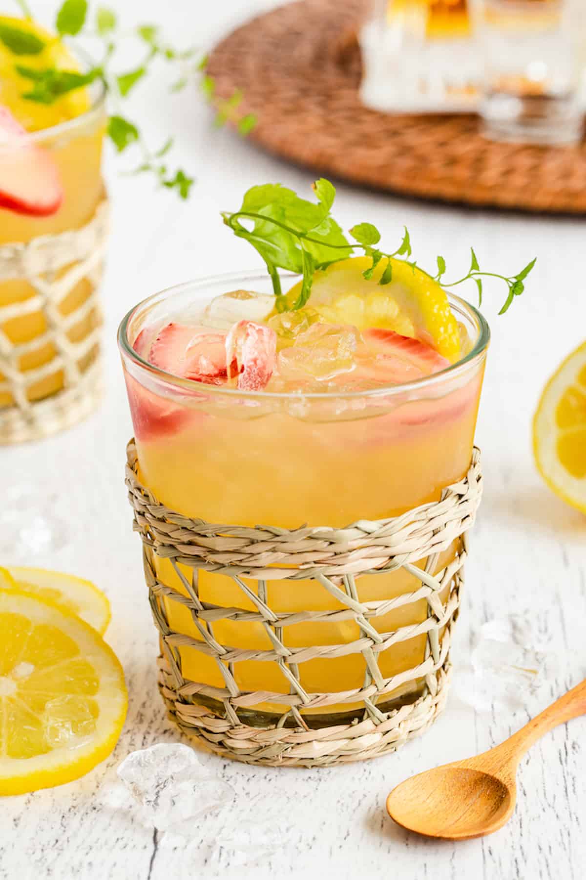 A spiked Arnold Palmer in a clear glass set in a woven drink holder.