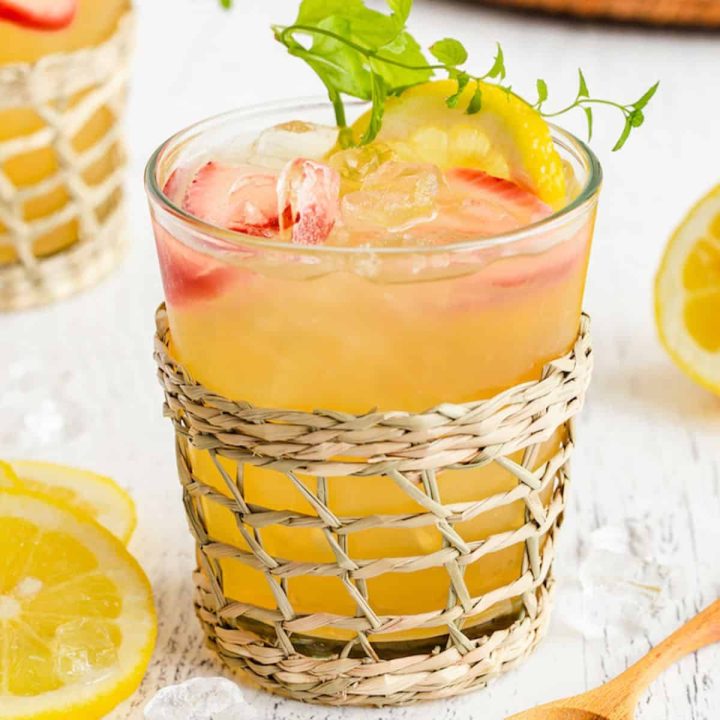 Close up of a spiked Arnold Palmer in a clear glass set in a woven drink holder.