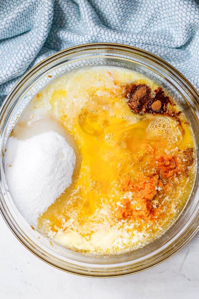 A large glass bowl with mashed sweet potato, eggs, butter, sugar and spices before being mixed together.