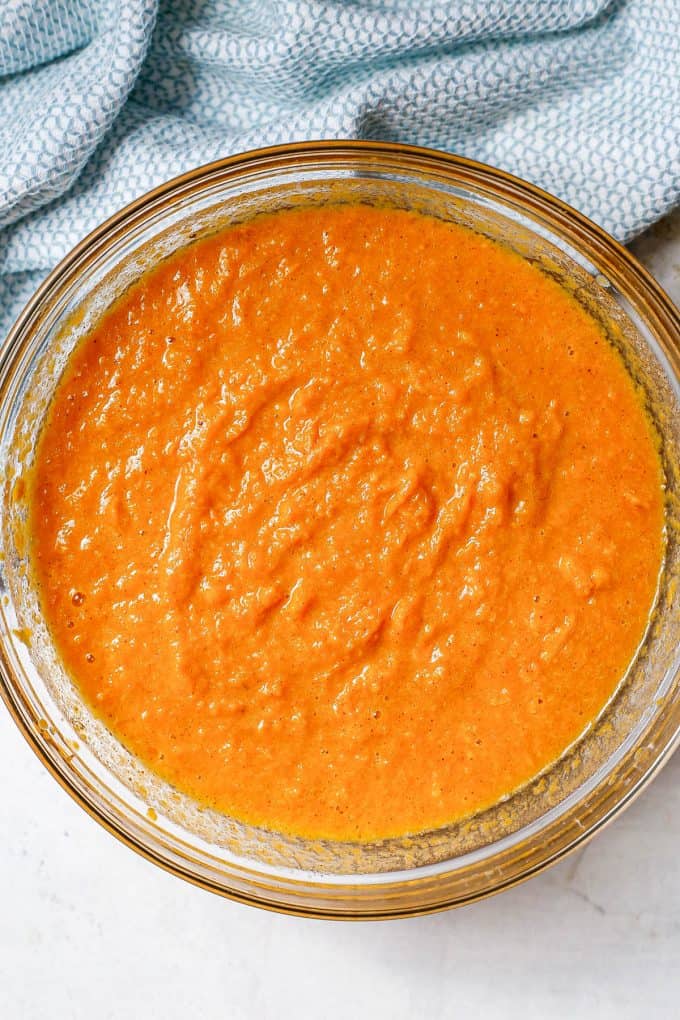 A large glass bowl with the filling of a sweet potato pie mixed together.