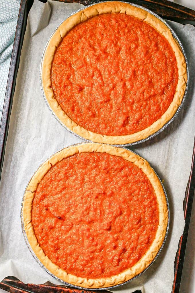 Two baked sweet potato pies on a parchment paper lined baking sheet.