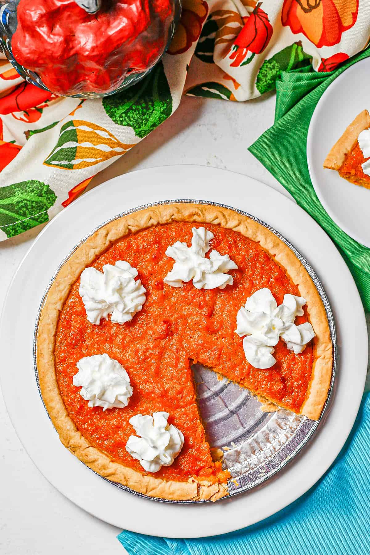 A sweet potato pie served on a white plate with whipped cream on top.