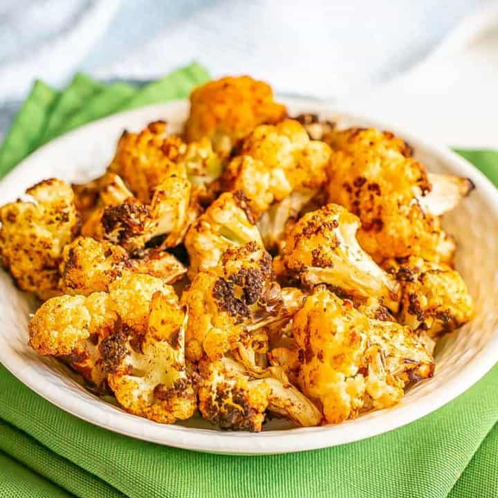 Close up of browned cauliflower florets served in a white bowl.