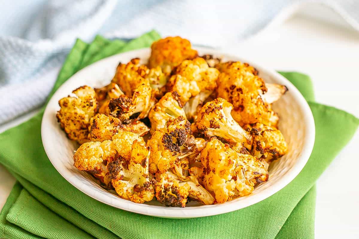 Close up of browned cauliflower florets served in a white bowl.