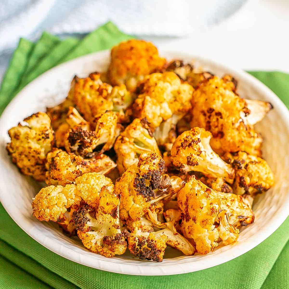 Close up of cooked cauliflower florets in a white bowl.