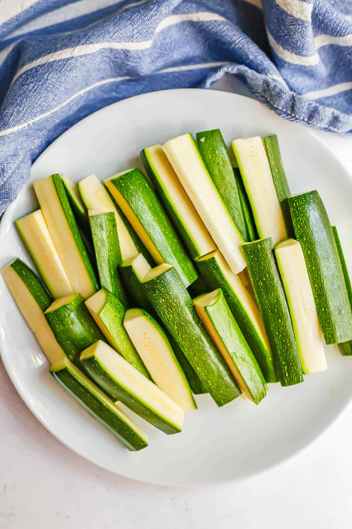 Cut zucchini sticks in a white bowl.