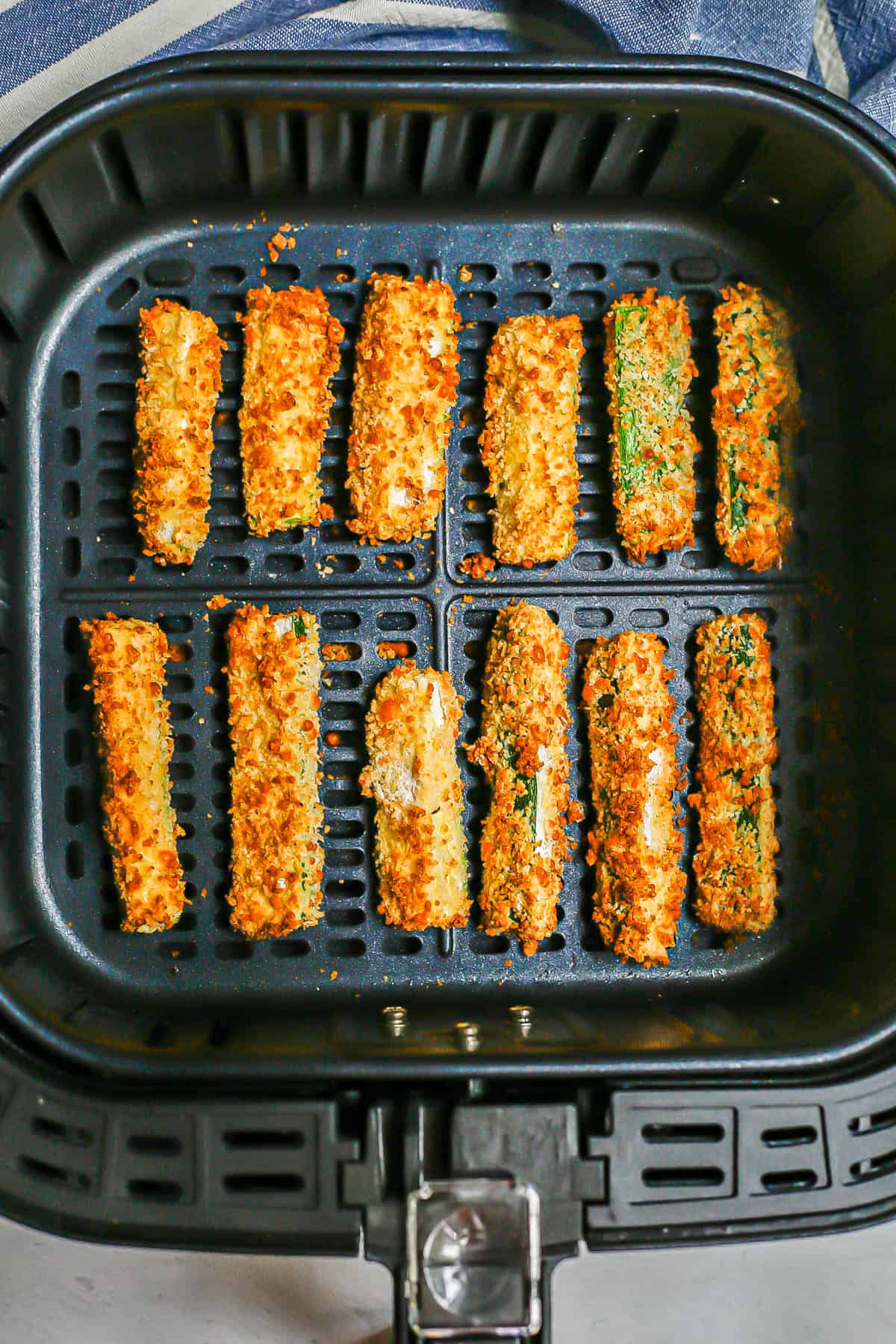 Two rows of zucchini fries cooked in an Air Fryer.